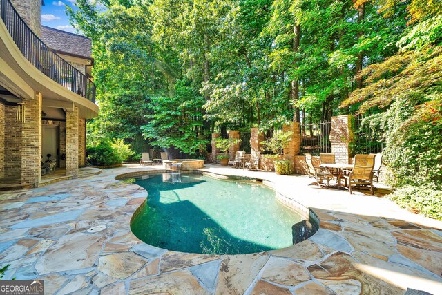 view of swimming pool with an outdoor fireplace and a patio