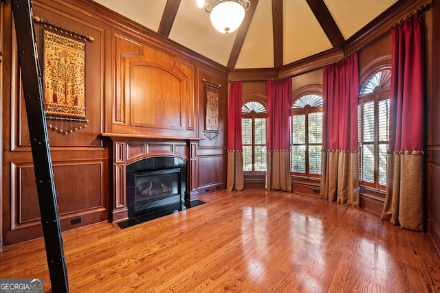 unfurnished living room featuring a tile fireplace, wood-type flooring, and high vaulted ceiling