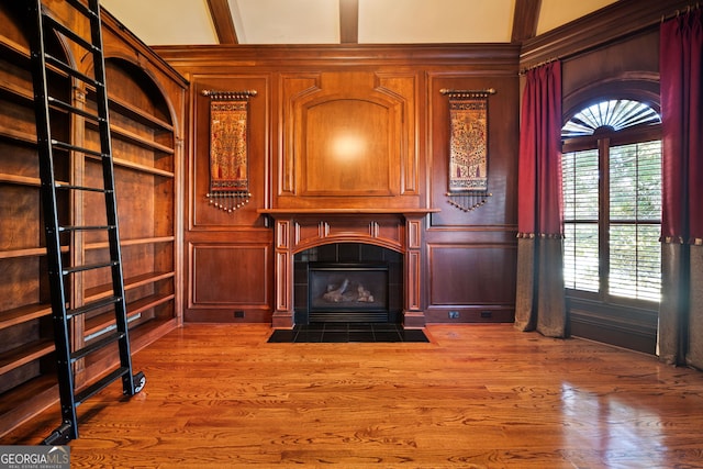 unfurnished living room with a fireplace, built in features, and wood walls