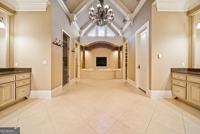 bathroom with vanity, a notable chandelier, high vaulted ceiling, and a premium fireplace