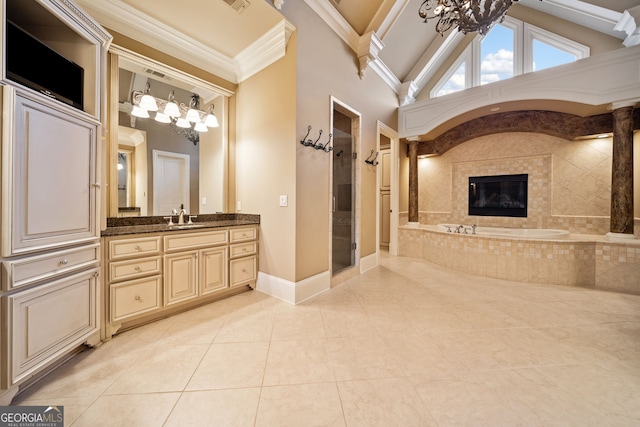 bathroom with a tile fireplace, vanity, ornamental molding, shower with separate bathtub, and a chandelier