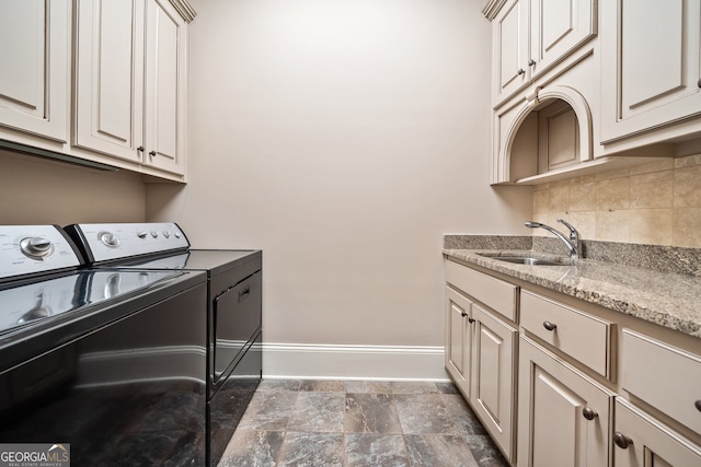 clothes washing area with cabinets, sink, and washer and dryer