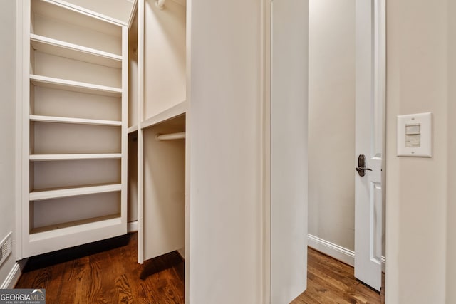 walk in closet with dark wood-type flooring