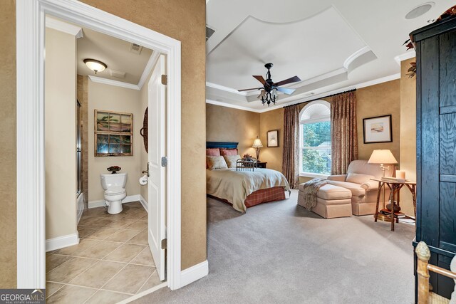 carpeted bedroom featuring a tray ceiling, crown molding, ceiling fan, and ensuite bathroom