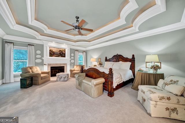 bedroom featuring a raised ceiling, light colored carpet, ceiling fan, and multiple windows