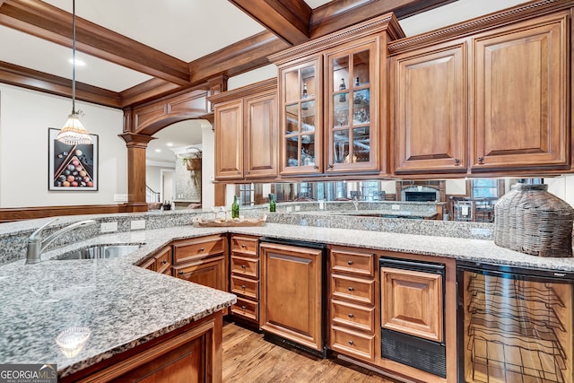 kitchen with decorative light fixtures, sink, beam ceiling, and light stone countertops