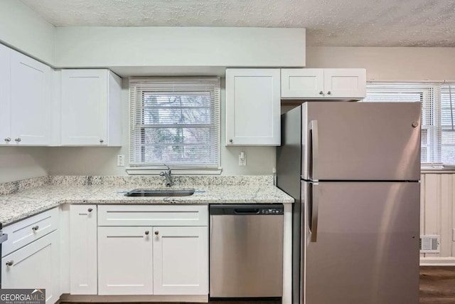 kitchen with white cabinetry, appliances with stainless steel finishes, sink, and light stone counters