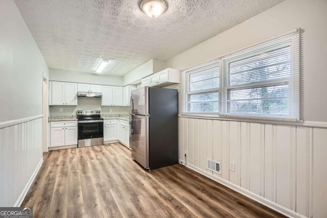 kitchen featuring appliances with stainless steel finishes, light wood-type flooring, a textured ceiling, and white cabinets