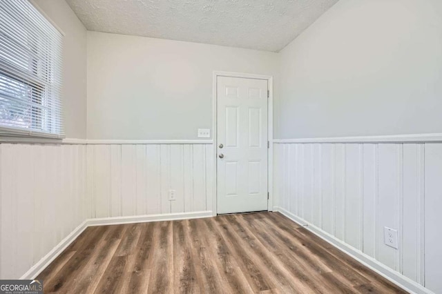 unfurnished room with dark wood-type flooring and a textured ceiling