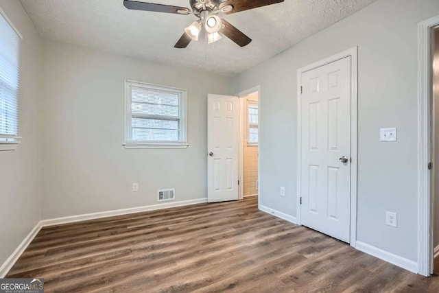 unfurnished bedroom featuring dark hardwood / wood-style floors, a textured ceiling, and ceiling fan