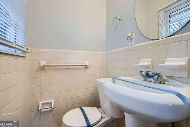 bathroom with toilet, sink, and tile walls