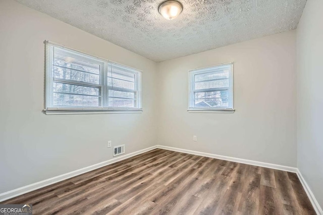 unfurnished room with dark hardwood / wood-style flooring, a healthy amount of sunlight, and a textured ceiling