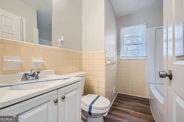 bathroom with wood-type flooring, tile walls, vanity, and toilet