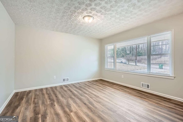 unfurnished room with dark hardwood / wood-style flooring and a textured ceiling