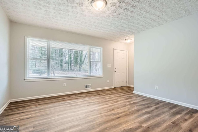 spare room featuring wood-type flooring and a textured ceiling