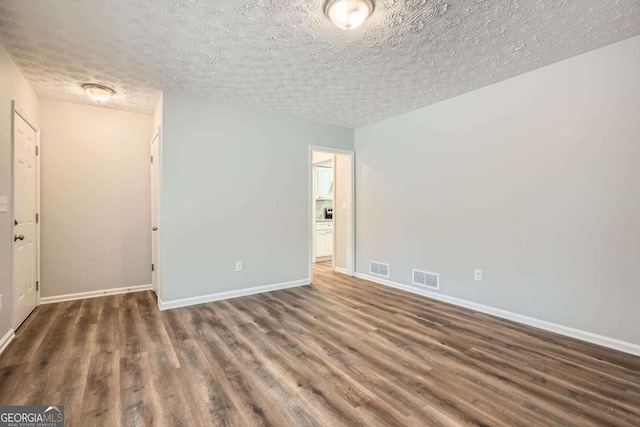 unfurnished room with dark wood-type flooring and a textured ceiling