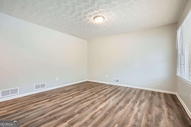 empty room featuring dark hardwood / wood-style flooring and a textured ceiling