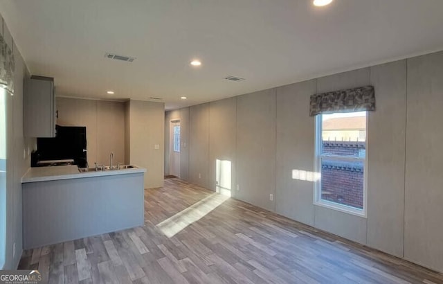 kitchen with sink, refrigerator, gray cabinetry, kitchen peninsula, and light wood-type flooring