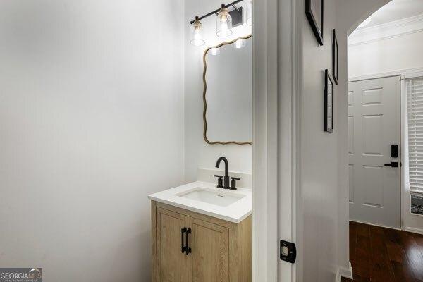 bathroom with hardwood / wood-style flooring, ornamental molding, and vanity