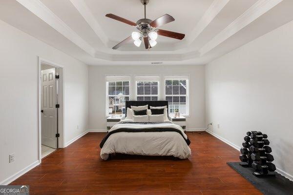 bedroom featuring dark wood-type flooring, ceiling fan, and a tray ceiling