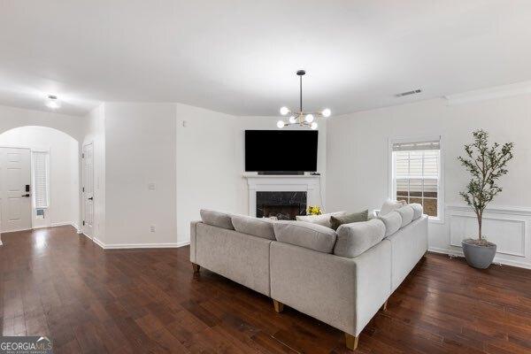 living room with a notable chandelier, a fireplace, and dark hardwood / wood-style floors