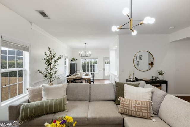 living room with an inviting chandelier, ornamental molding, plenty of natural light, and wood-type flooring