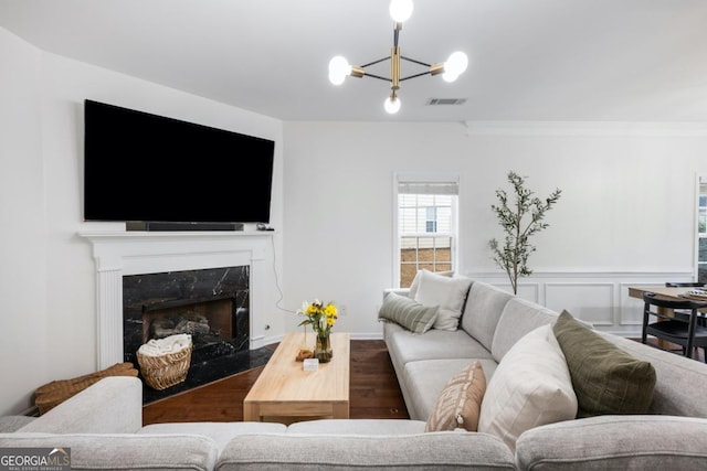 living room featuring hardwood / wood-style floors, crown molding, a fireplace, and a chandelier