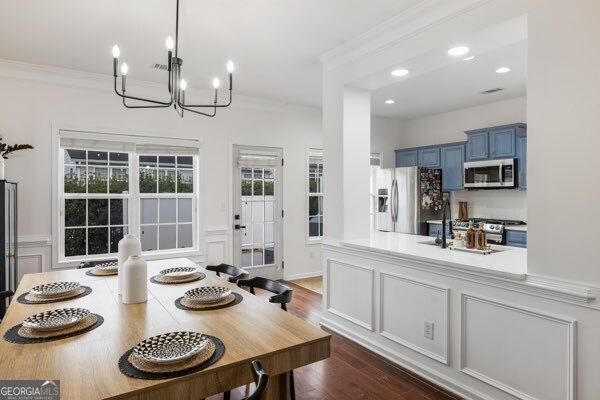 dining area with ornamental molding, a chandelier, and dark hardwood / wood-style flooring