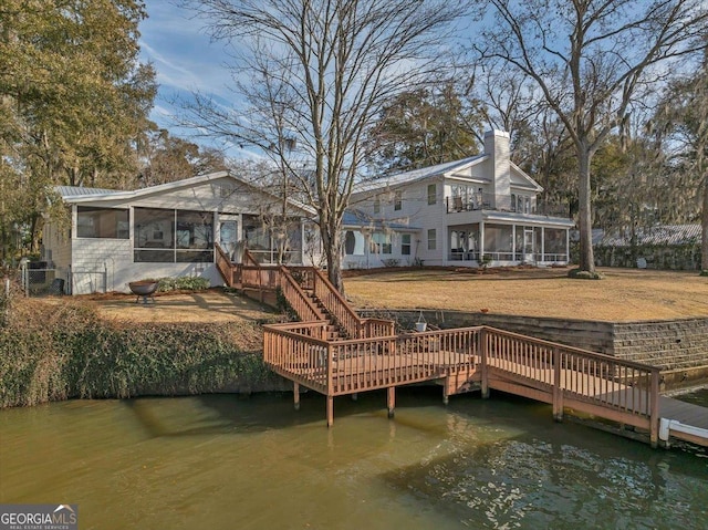 rear view of property featuring stairway, a sunroom, a water view, and a chimney