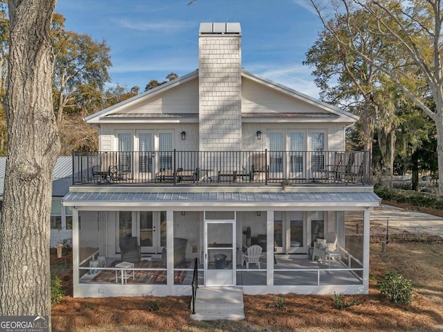 back of property featuring a sunroom, a chimney, and french doors