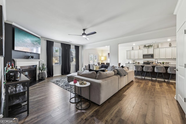 living room with crown molding, dark wood-type flooring, and ceiling fan