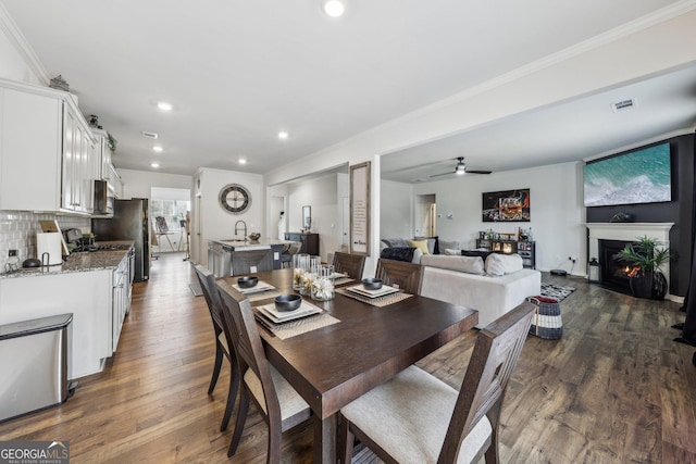 dining area with crown molding, ceiling fan, and dark hardwood / wood-style flooring