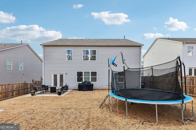 rear view of house featuring a trampoline, a patio area, and french doors