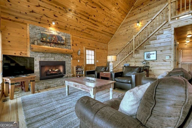 living room featuring high vaulted ceiling, a fireplace, wooden walls, wood-type flooring, and wooden ceiling