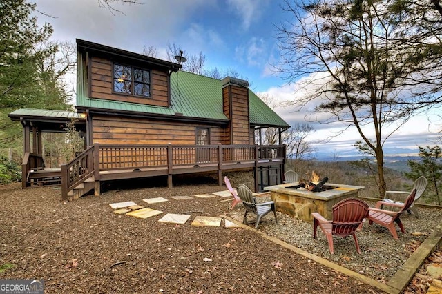 rear view of house with a deck and an outdoor fire pit