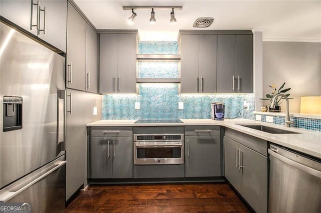 kitchen featuring stainless steel appliances, gray cabinets, sink, and decorative backsplash