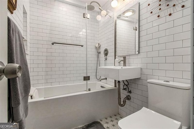 full bathroom with tile walls, tiled shower / bath, sink, and toilet