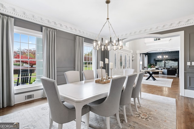 dining area with a notable chandelier, ornamental molding, and hardwood / wood-style floors