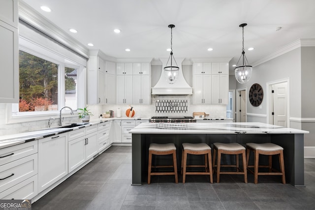 kitchen featuring a center island, a breakfast bar area, white cabinets, and decorative light fixtures