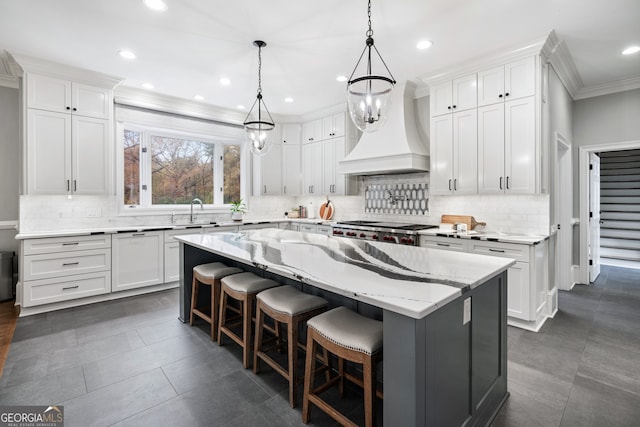 kitchen featuring a breakfast bar area, a center island, custom range hood, and white cabinets