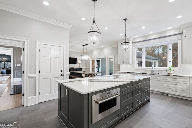 kitchen with white cabinetry, hanging light fixtures, a center island, decorative backsplash, and stainless steel oven