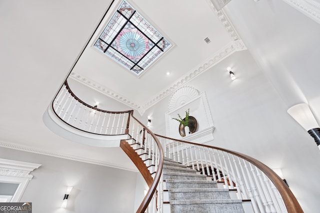 stairway featuring crown molding and a towering ceiling