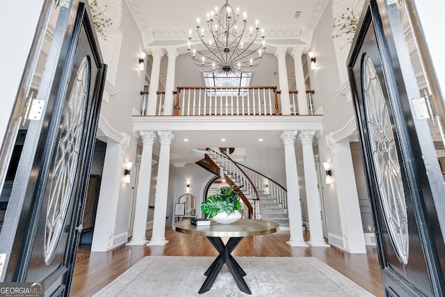 entryway with a towering ceiling, ornamental molding, decorative columns, and dark hardwood / wood-style floors