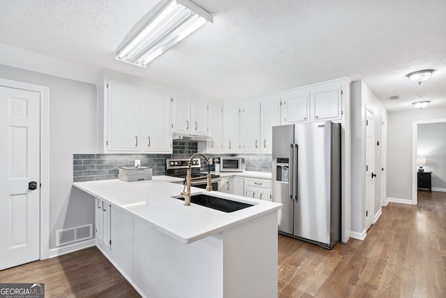 kitchen featuring stainless steel appliances, kitchen peninsula, and white cabinets