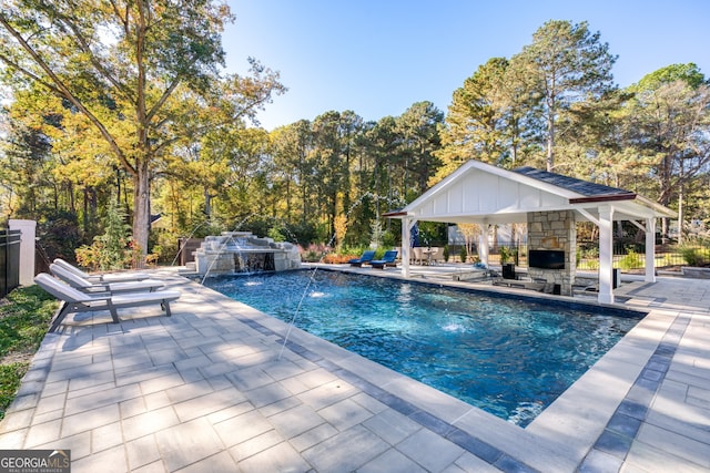 view of swimming pool with a gazebo, pool water feature, a patio, and an outdoor stone fireplace