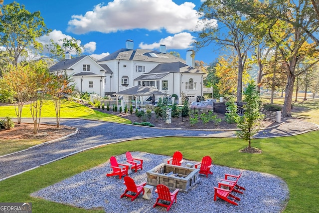 back of property featuring a gazebo, a yard, and an outdoor fire pit