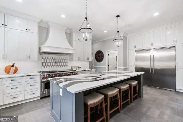 kitchen with white cabinetry, hanging light fixtures, a center island, high end appliances, and custom range hood