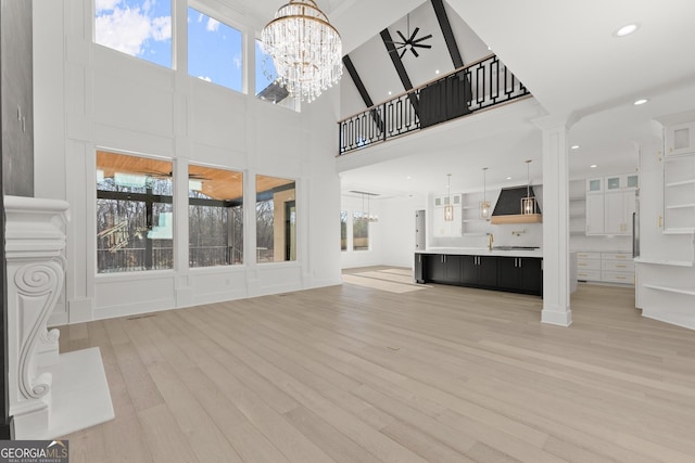 1041 Fleeman Rd, Hoschton, GA 30548 - unfurnished living room with a chandelier, light wood-style flooring, a towering ceiling, recessed lighting, and decorative columns