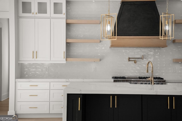 1041 Fleeman Rd, Hoschton, GA 30548 - kitchen with light stone counters, backsplash, white cabinetry, dark cabinetry, and glass insert cabinets