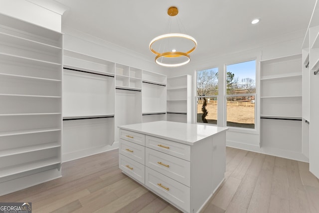 spacious closet featuring an inviting chandelier and light hardwood / wood-style flooring